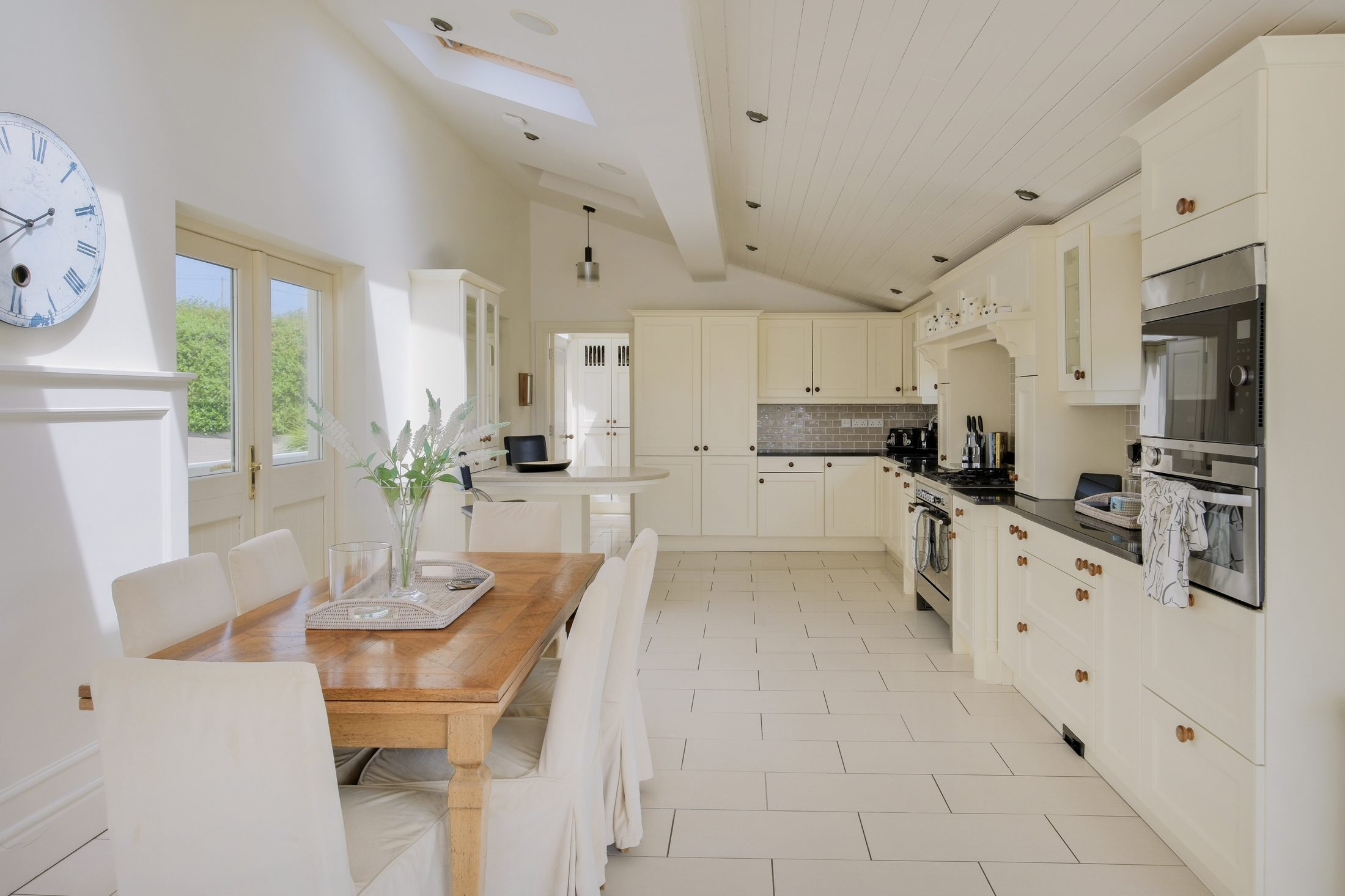 Open-plan kitchen with cream cabinetry and farmhouse dining table