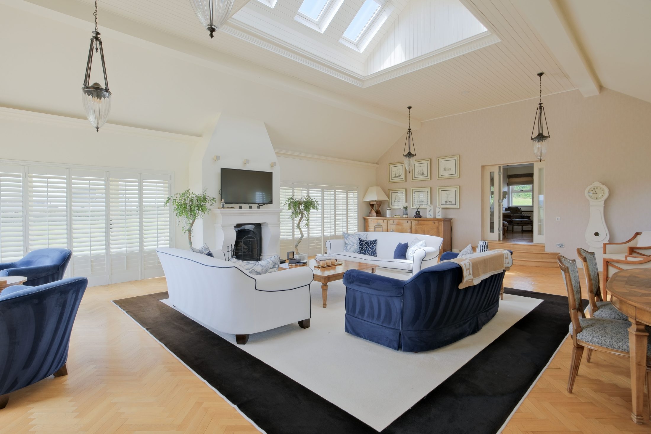 Living room with vaulted ceiling, skylights and navy and white furnishings